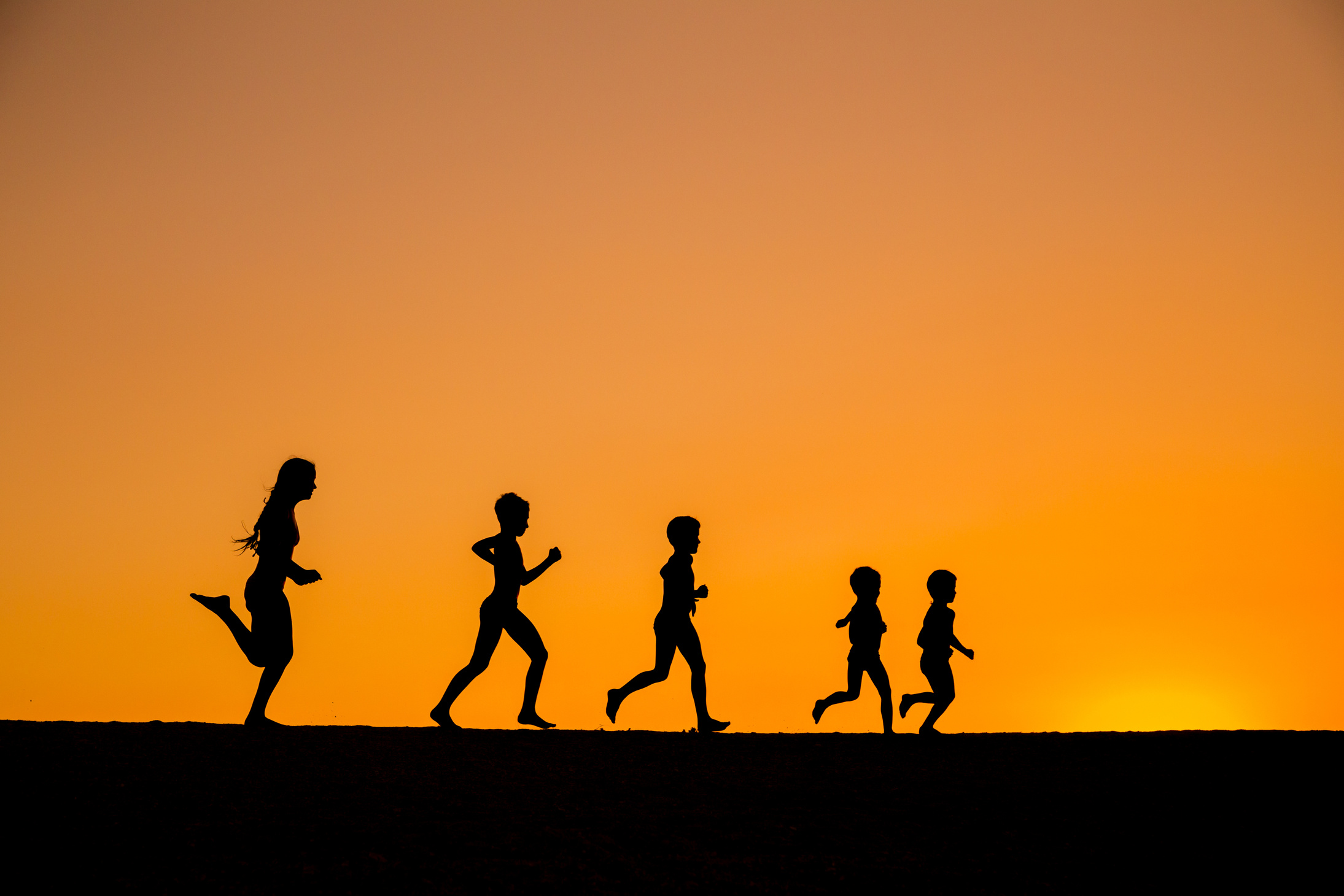 silhouette of running kids against sunset